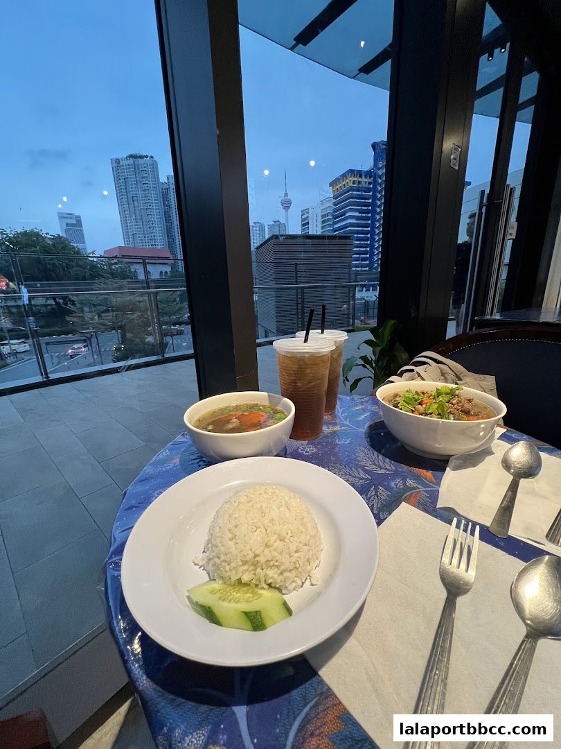A table setting with rice, soup, and drinks, overlooking a city skyline.