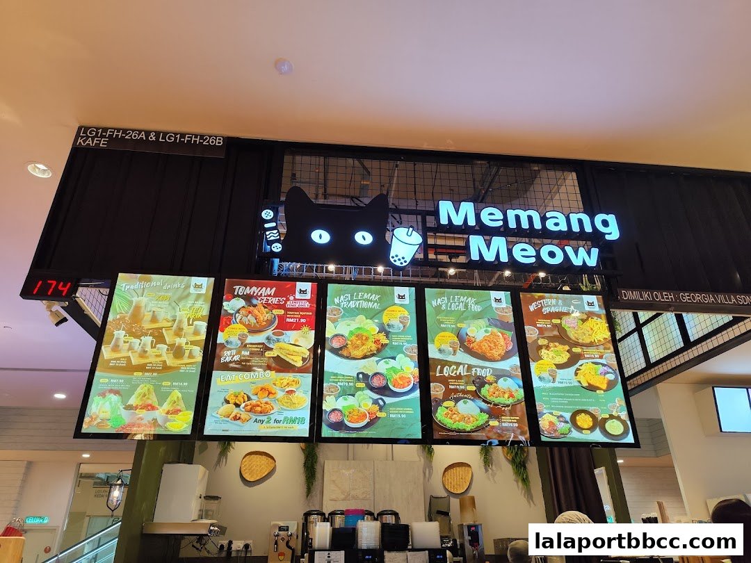 A brightly lit menu board displaying various food and drink options at Memang Meow.