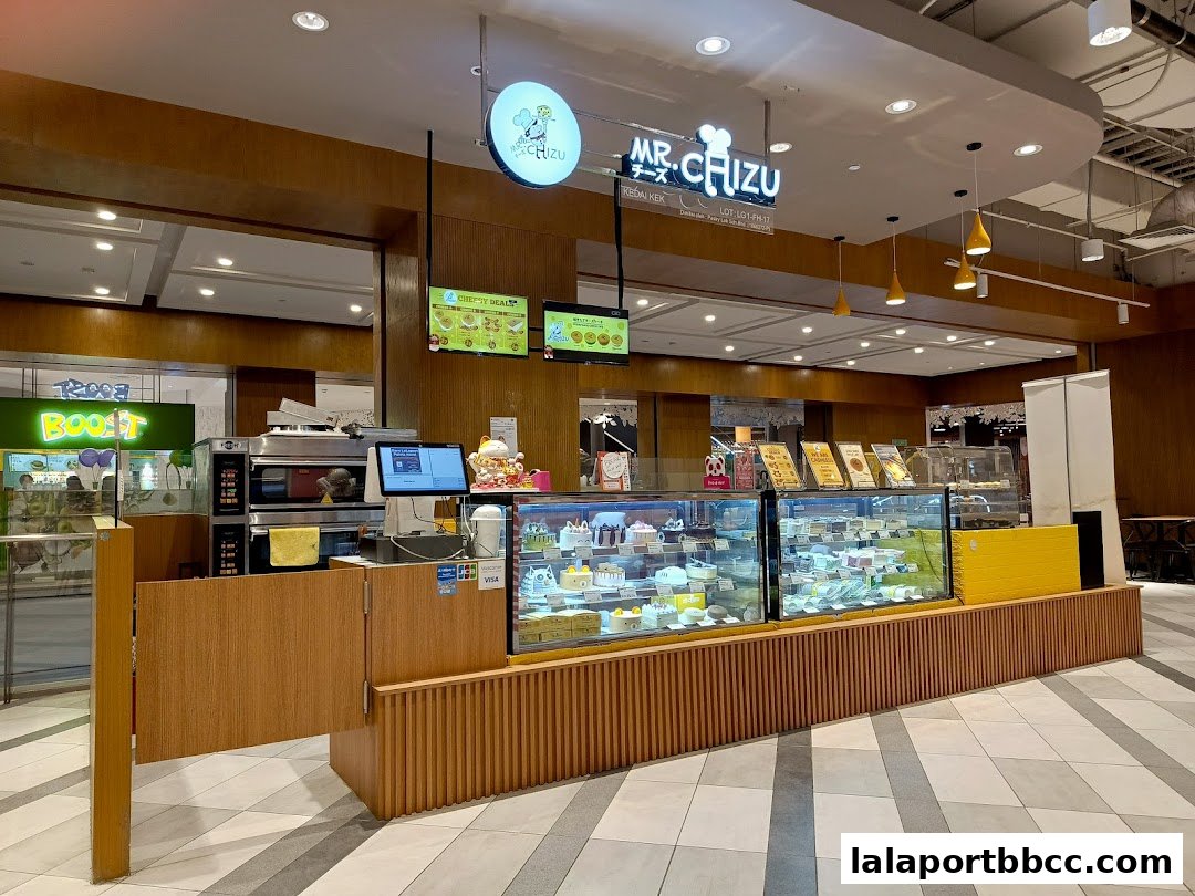 A brightly lit bakery counter displaying a variety of cakes and pastries.