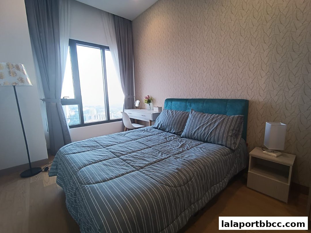 A bedroom with a bed, dresser, and large window with city view.