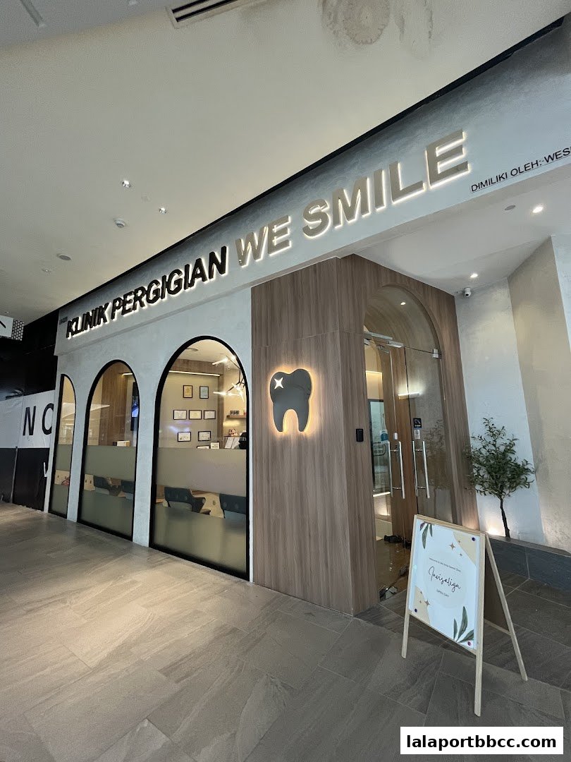 The modern entrance of WeSmile Dental Clinic with illuminated signage and a welcoming A-frame sign.