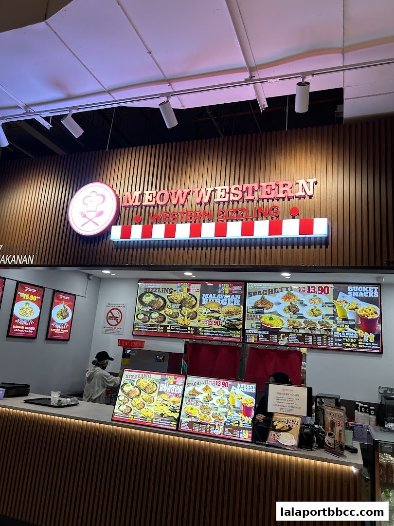 A food counter with digital menus displaying Western and Malaysian dishes.