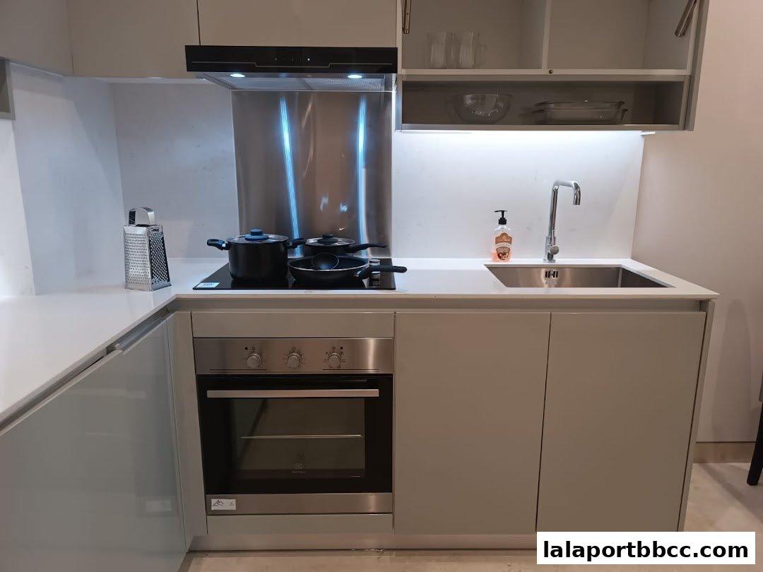 A modern, compact kitchen with an oven, sink, stovetop, and cooking utensils.