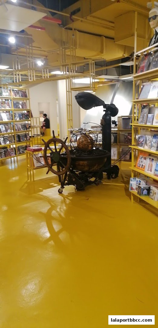 Interior of a shop with yellow floors, shelves filled with books and magazines, and unique decor.