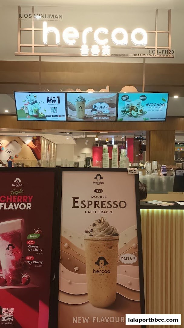 A beverage shop called Hercaa with digital displays showcasing drinks and promotional posters.