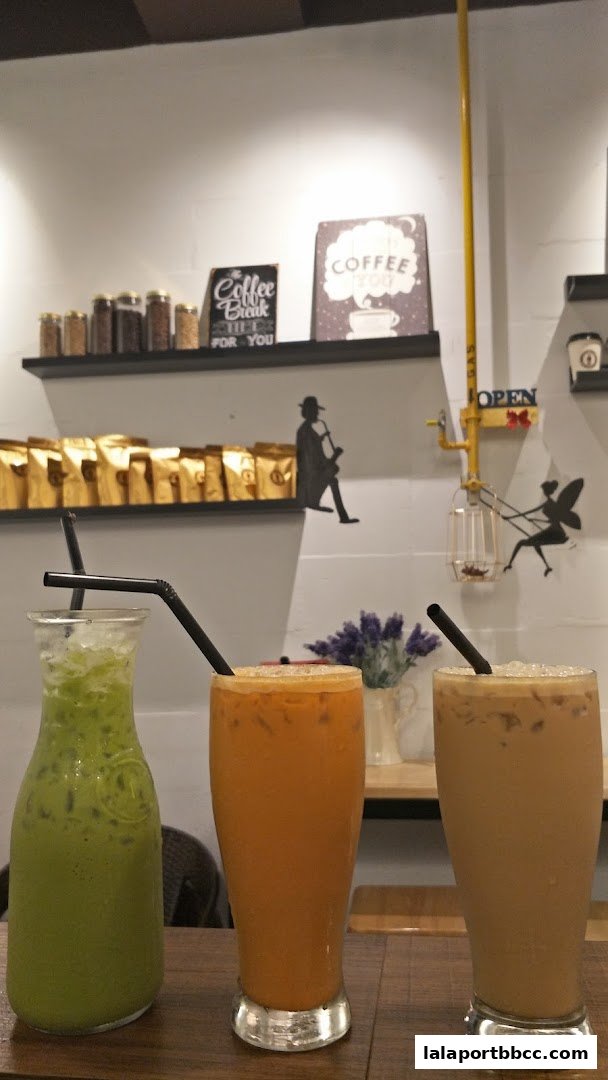 Three iced beverages, including matcha, Thai tea, and coffee, are displayed on a wooden table.