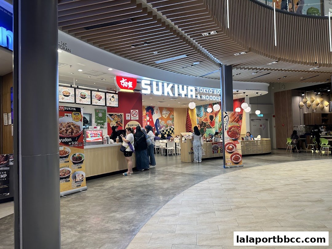 The Sukiya Tokyo Bowls & Noodles shop front with customers ordering at the counter.
