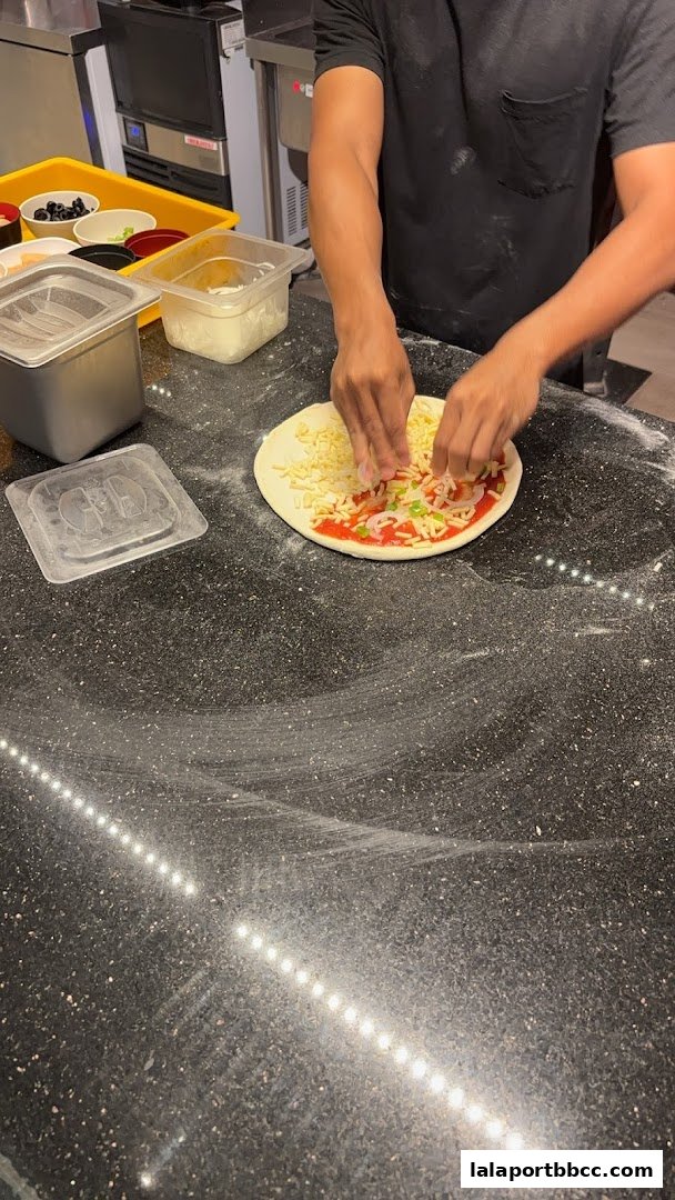 A chef is preparing a pizza by adding cheese and toppings to the dough.