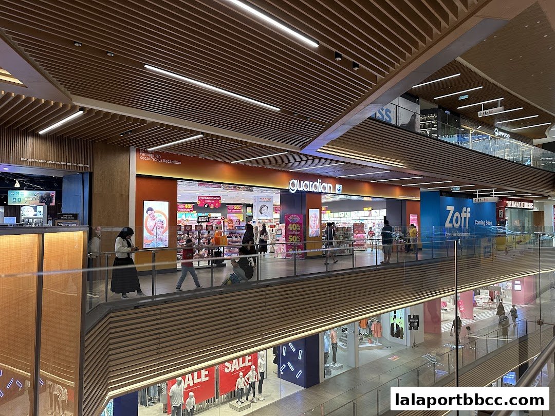 A view of the Guardian store and surrounding shops on a mall level.