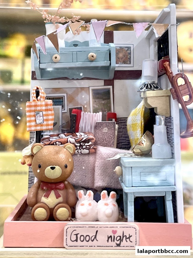 A miniature room scene with a teddy bear, bunnies, and decorative items.