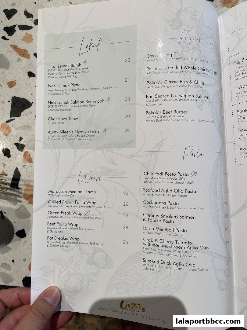 A menu from POKOK LaLaport featuring dishes under 'Lokal', 'Mains', 'Wraps', and 'Pasta' categories.