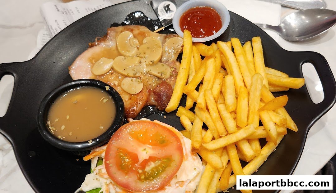A plate of food featuring a steak with mushroom sauce, french fries, coleslaw, and ketchup.