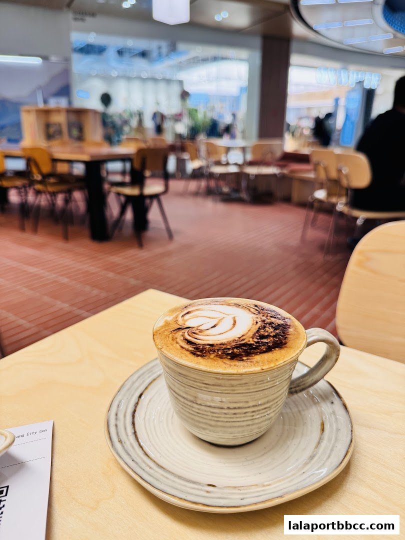 A close-up of a cappuccino with latte art, with a blurred cafe interior in the background.
