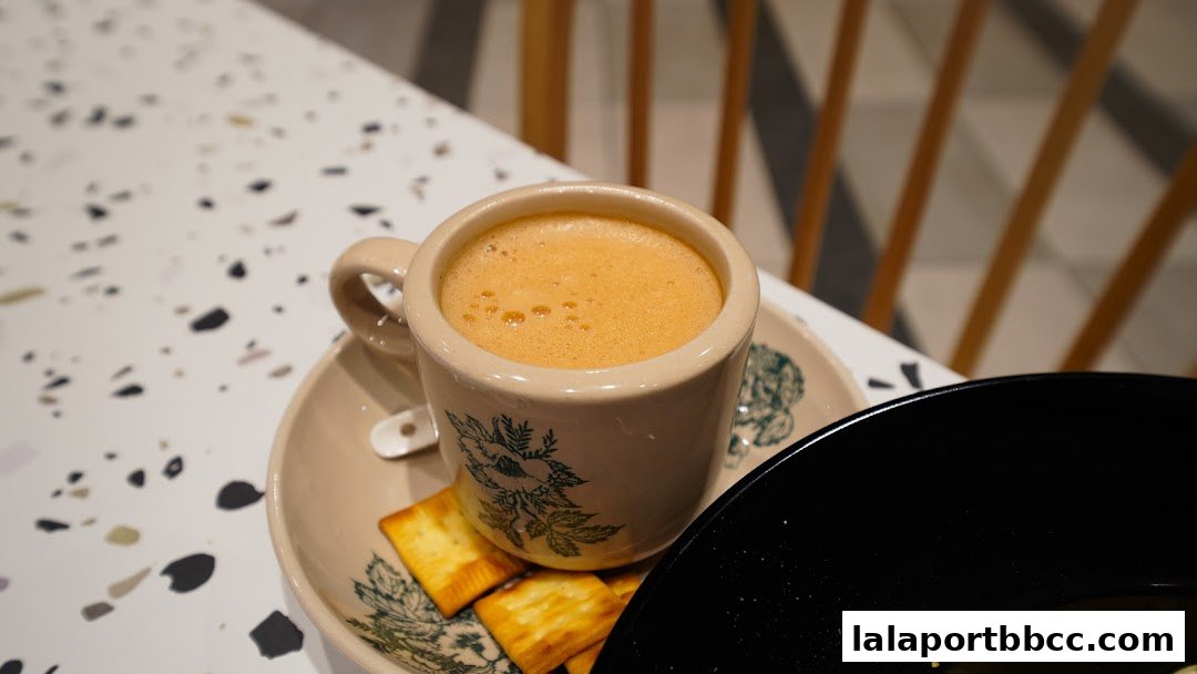 A close-up of a frothy beverage in a vintage mug with crackers on a saucer.