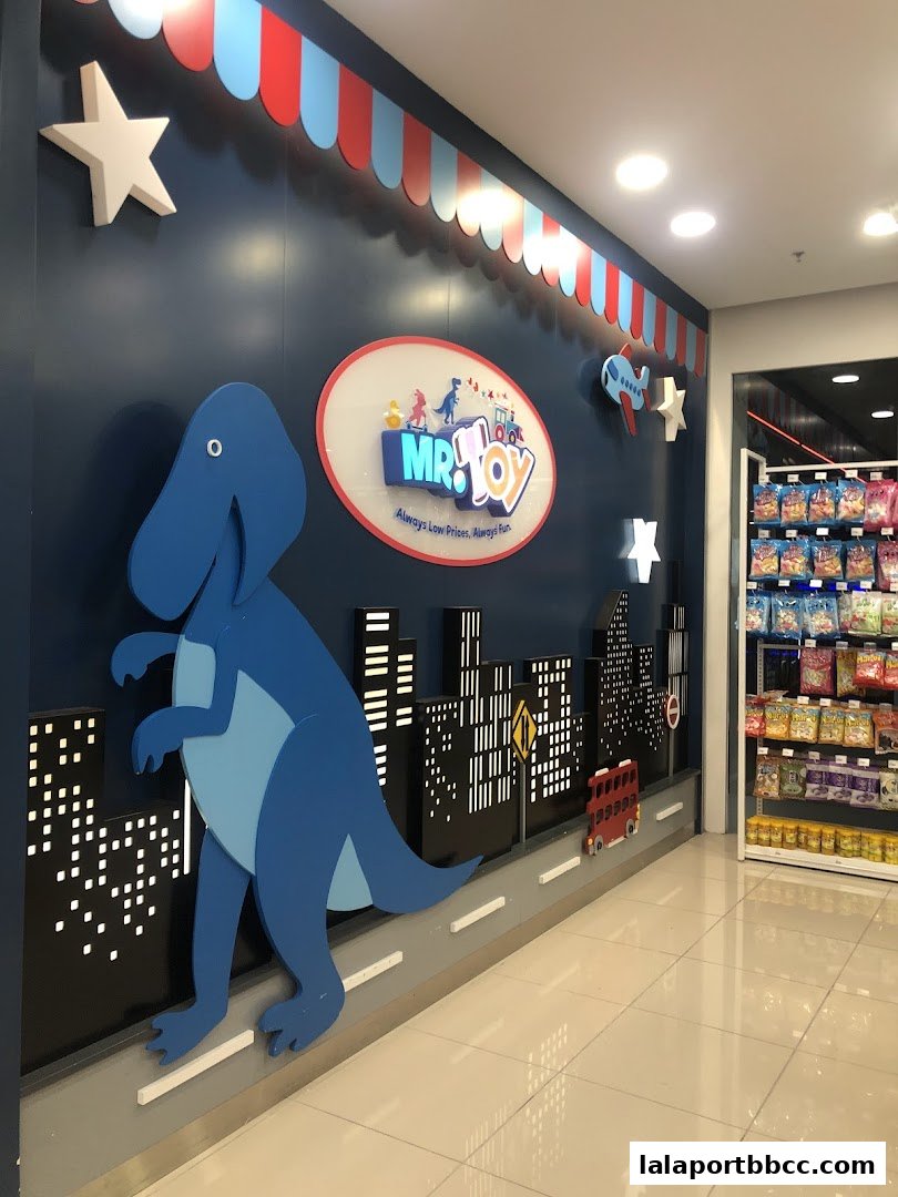 A colorful MR.TOY shop interior with a large dinosaur, city skyline, and shelves of toys.