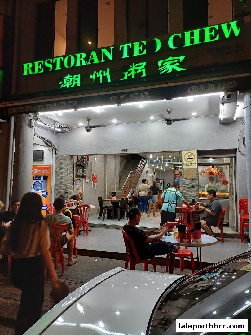 Restoran Teo Chew restaurant exterior at night with customers seated at tables.