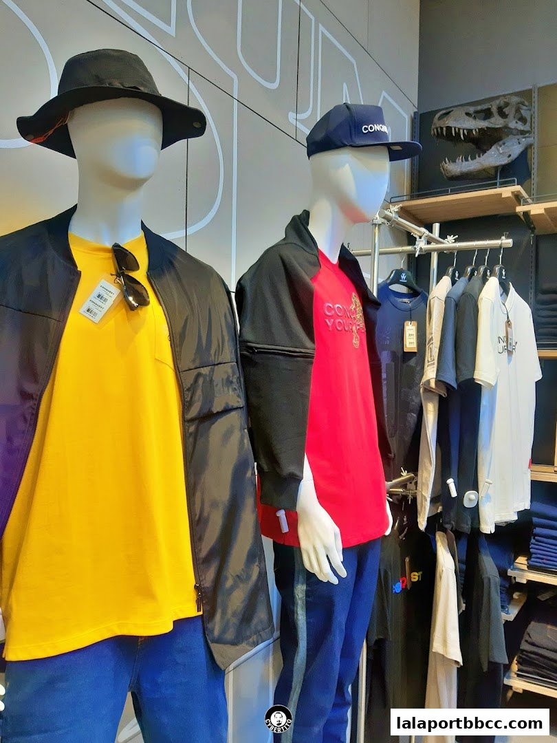Mannequins display casual outfits with t-shirts, jackets, hats, and jeans, alongside hanging apparel.