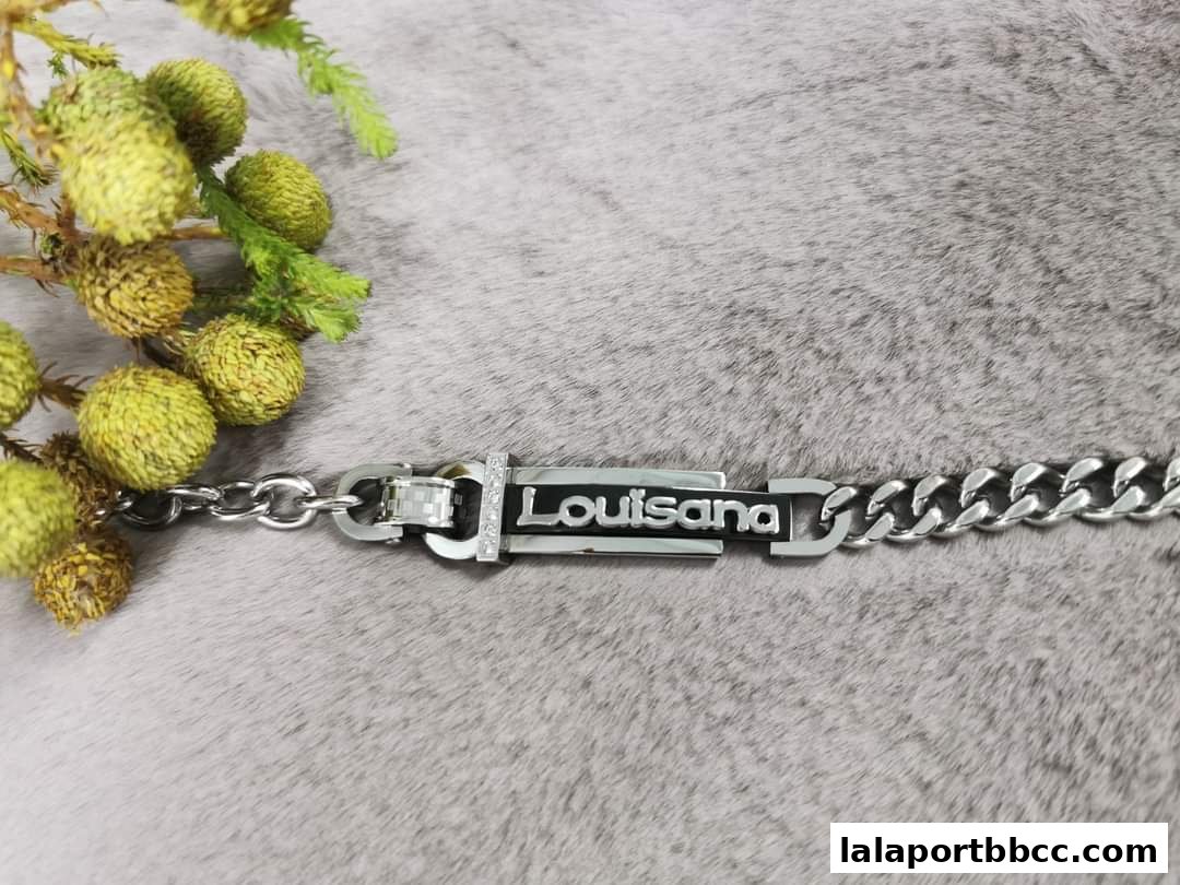 A close-up of a silver bracelet with the name 'Louisiana' on a textured gray background.