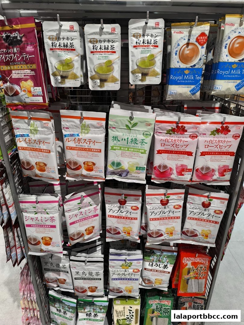 A display of various tea bags and powdered teas, including green tea, rooibos, jasmine, apple, and milk tea.