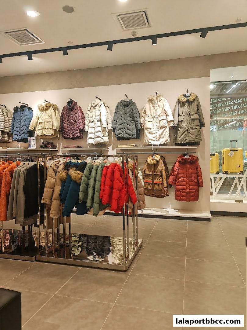 Interior view of a clothing store displaying a variety of winter jackets on racks and hangers.
