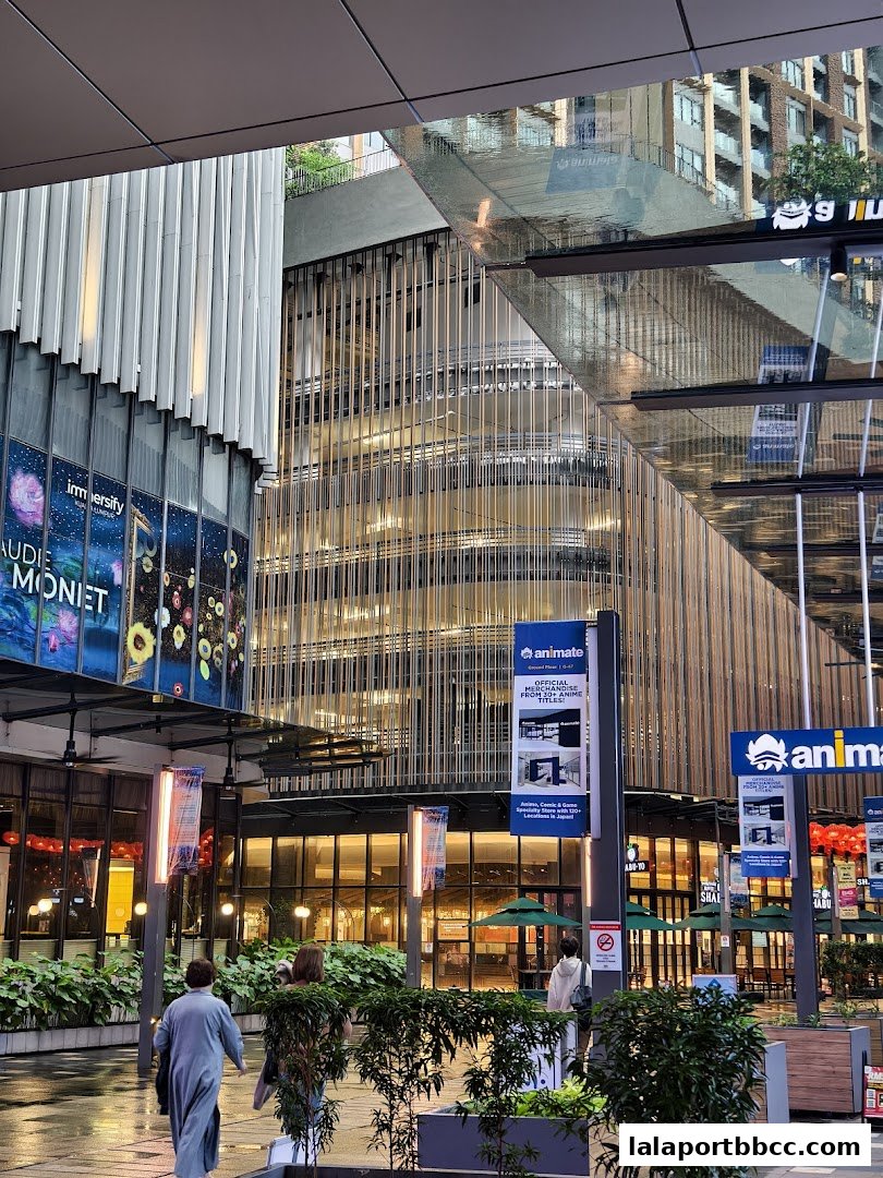 Modern building exterior with shops and people walking.