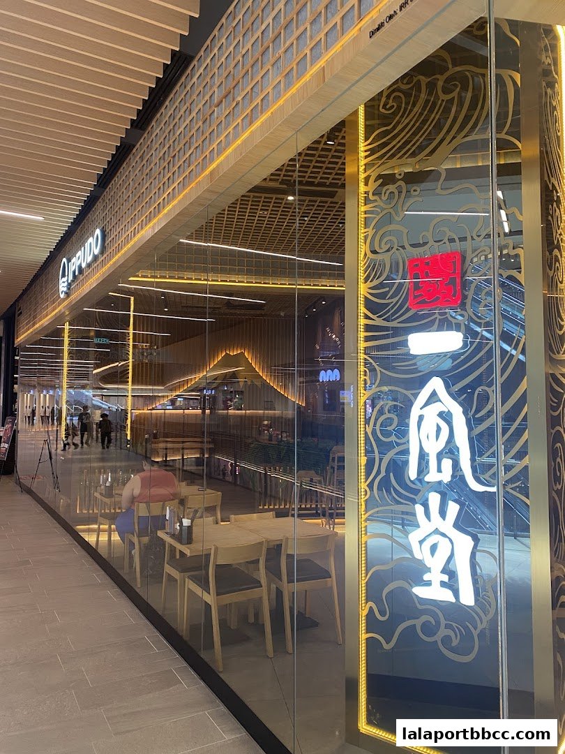 The exterior of IPPUDO LaLaport BBCC, a ramen restaurant, with a modern and inviting interior visible through glass.