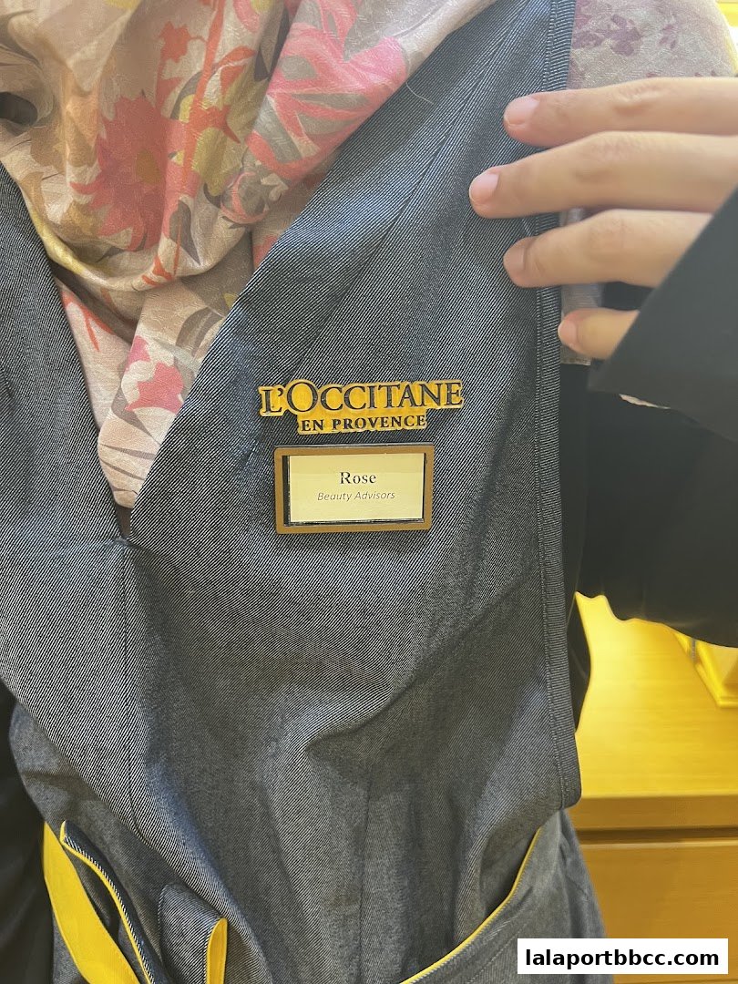 A close-up of a L'Occitane employee wearing a name tag and a floral scarf.