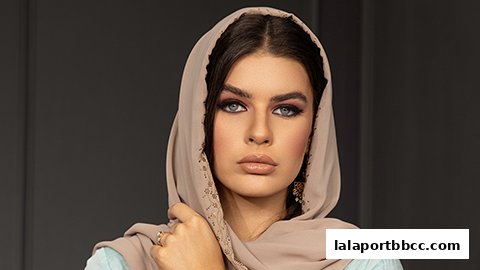 A woman wearing a hijab and makeup, posing for a fashion shoot.