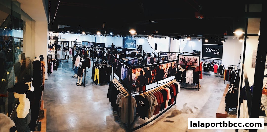 A wide-angle view of a modern clothing store interior with racks of apparel and mannequins.