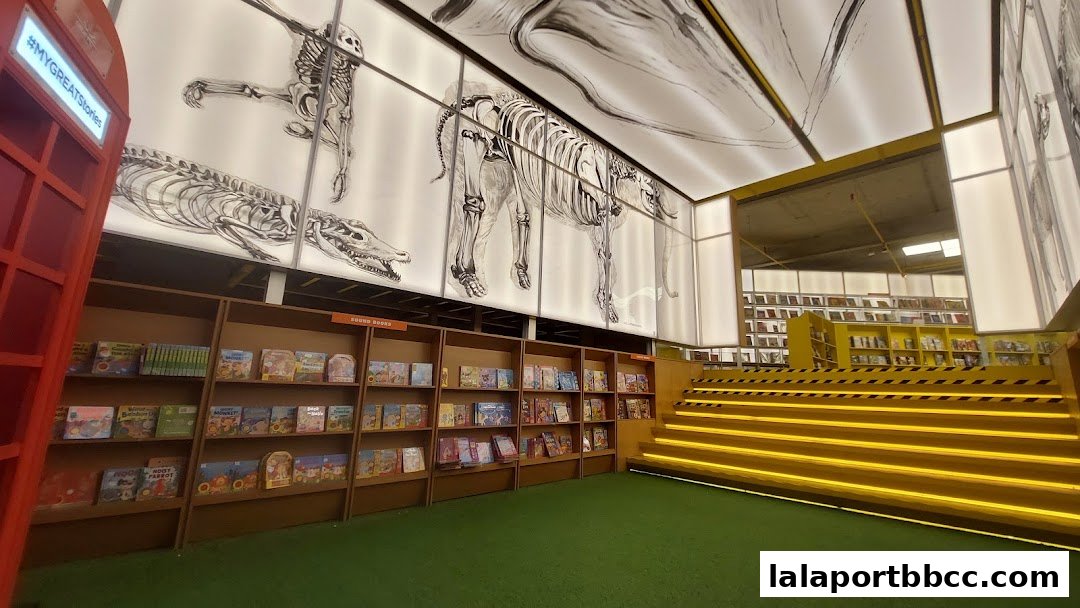 Interior of a bookstore with shelves of books, anatomical drawings on the ceiling, and illuminated stairs.