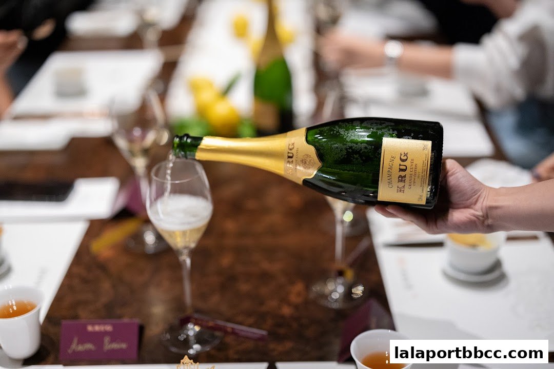 A hand pours Krug Champagne into a glass at a formal dining setting.
