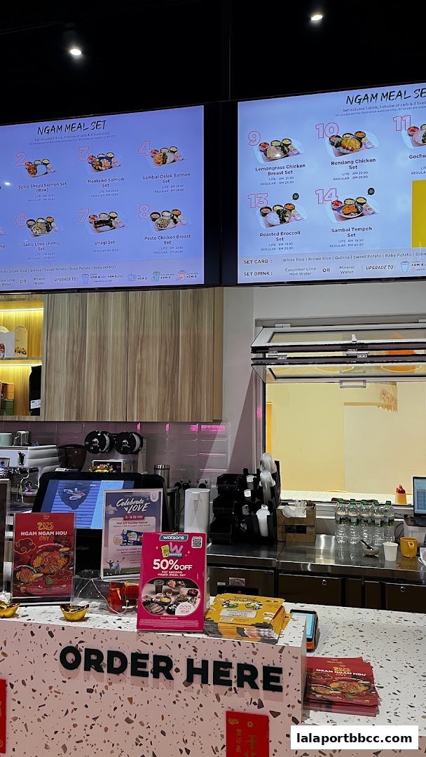 A counter with digital menus displaying meal sets and promotional flyers.