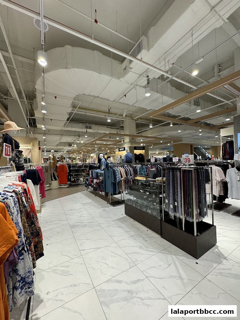 Interior view of a well-lit department store with clothing racks and displays.