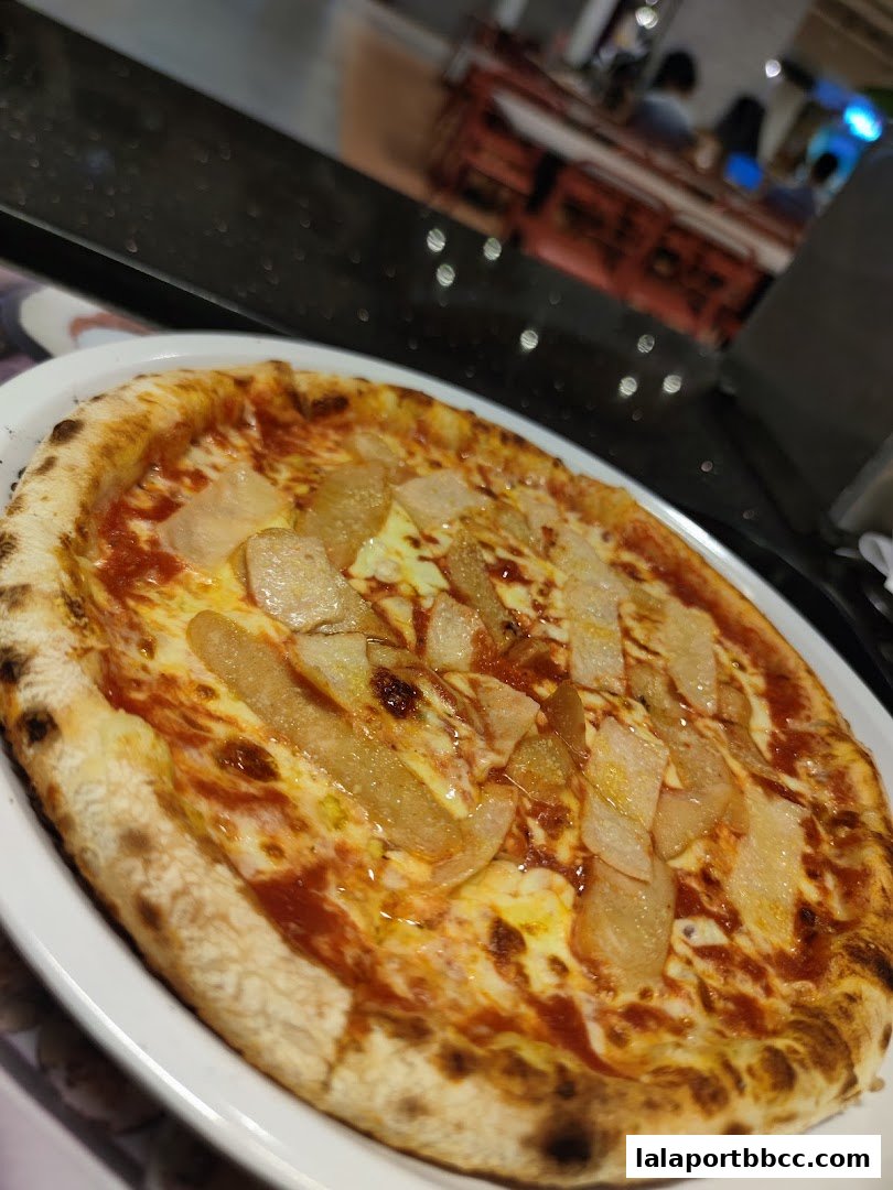 A delicious pizza with pear slices and melted cheese on a white plate.