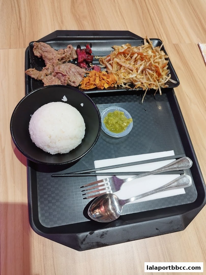 A teppanyaki meal with grilled meat, rice, vegetables, and dipping sauce on a tray.