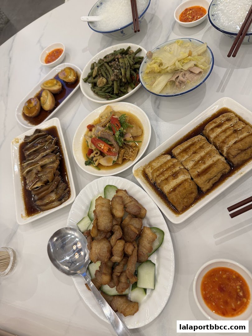 A spread of Teochew porridge and various side dishes, including braised pork, eggs, and vegetables.