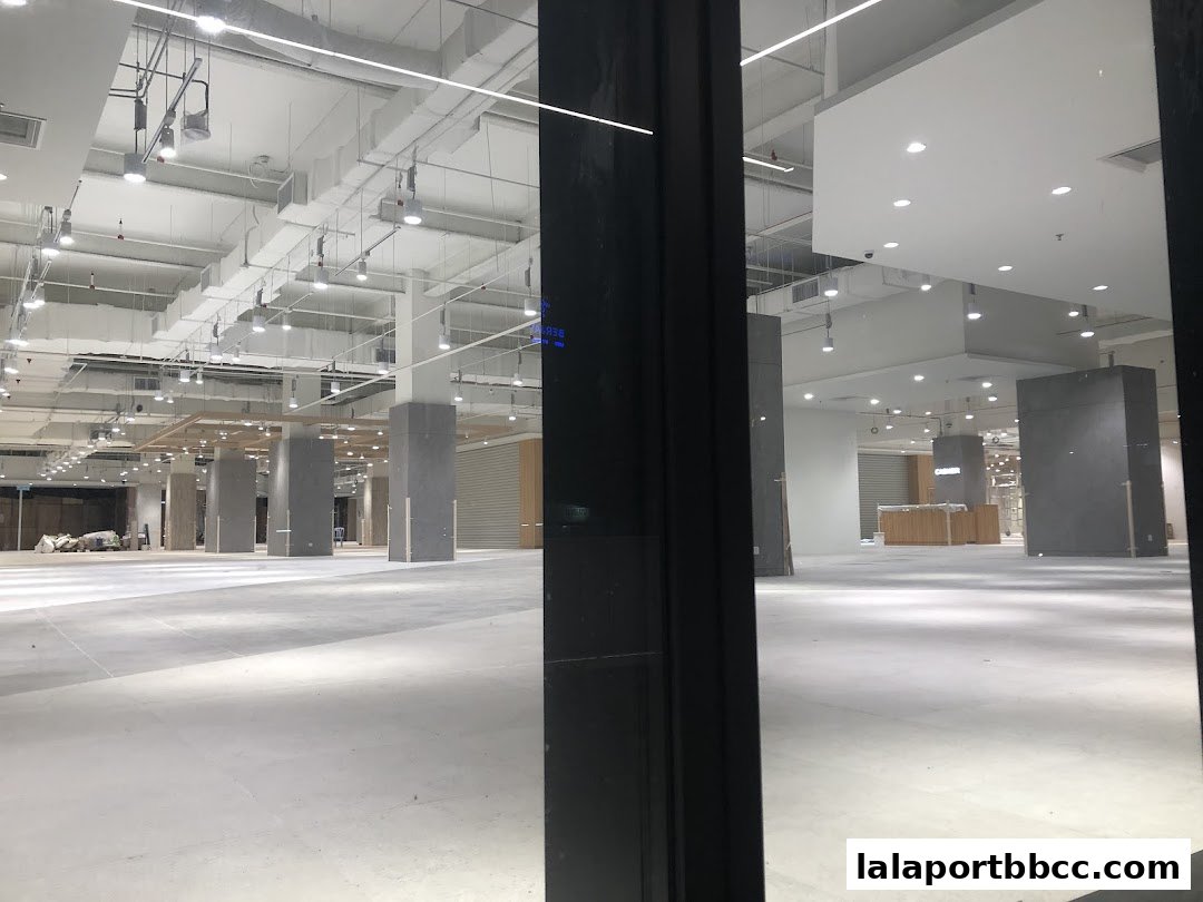 Interior view of a large, empty retail space with exposed ceilings and lighting.
