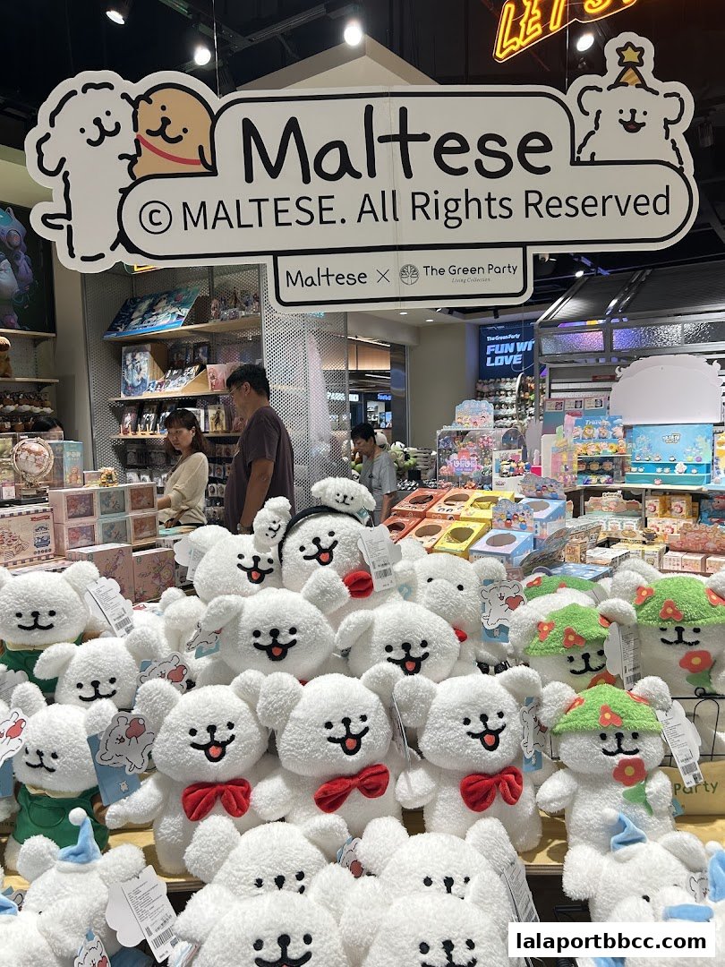 A display of numerous white plush toys with cute faces and red bows, branded as Maltese.