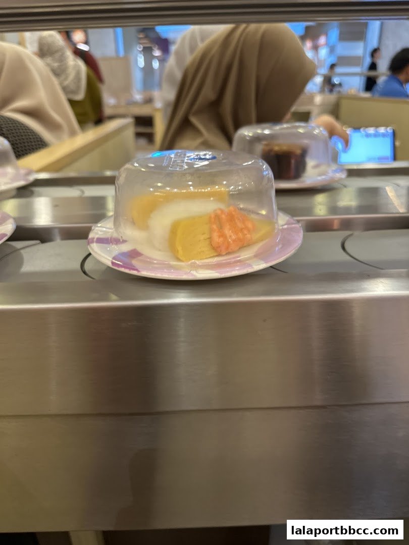 A plate of sushi with tamagoyaki and shrimp on a conveyor belt.