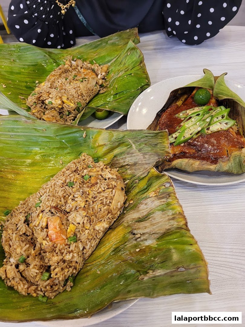 Two servings of fried rice and a dish of fish with okra, all presented on banana leaves.