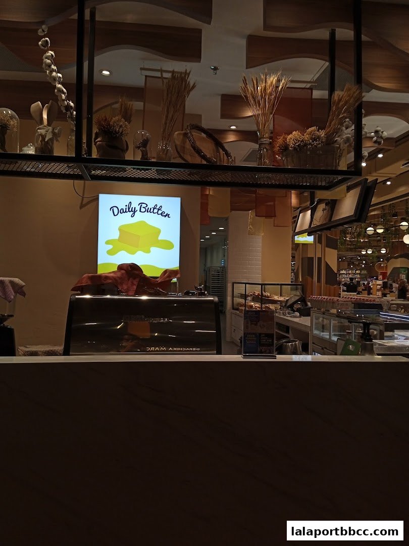 Interior view of a grocery store with a counter, coffee machine, and decorative elements.
