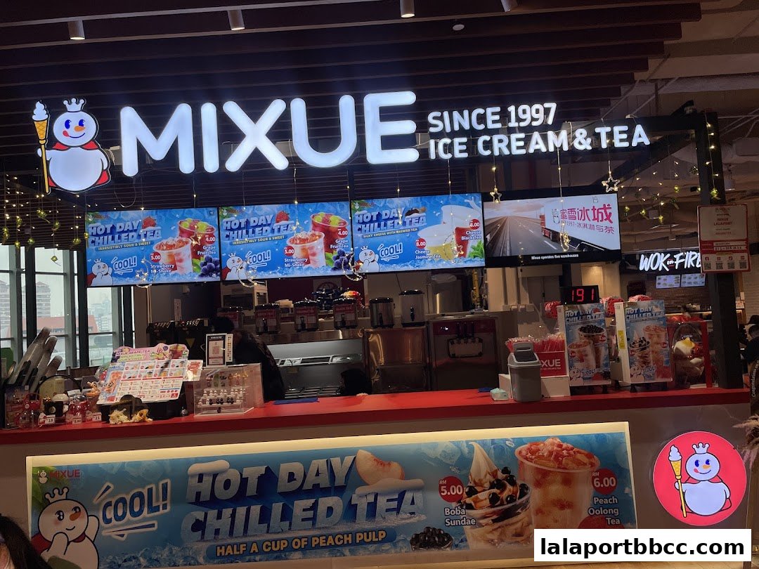The MIXUE ice cream and tea shop front with illuminated signage and digital menus displaying drinks.