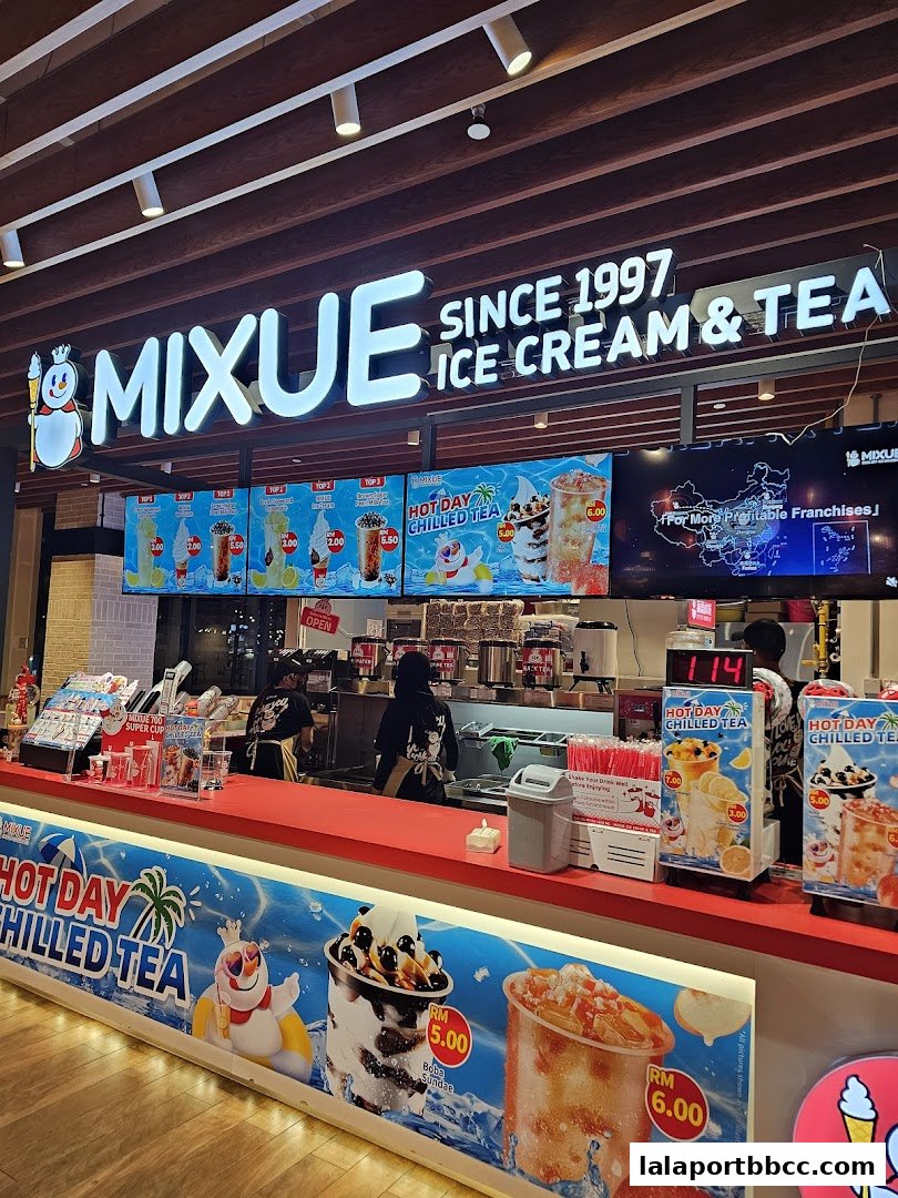 A Mixue Ice Cream & Tea shop counter with colorful product displays and staff serving customers.