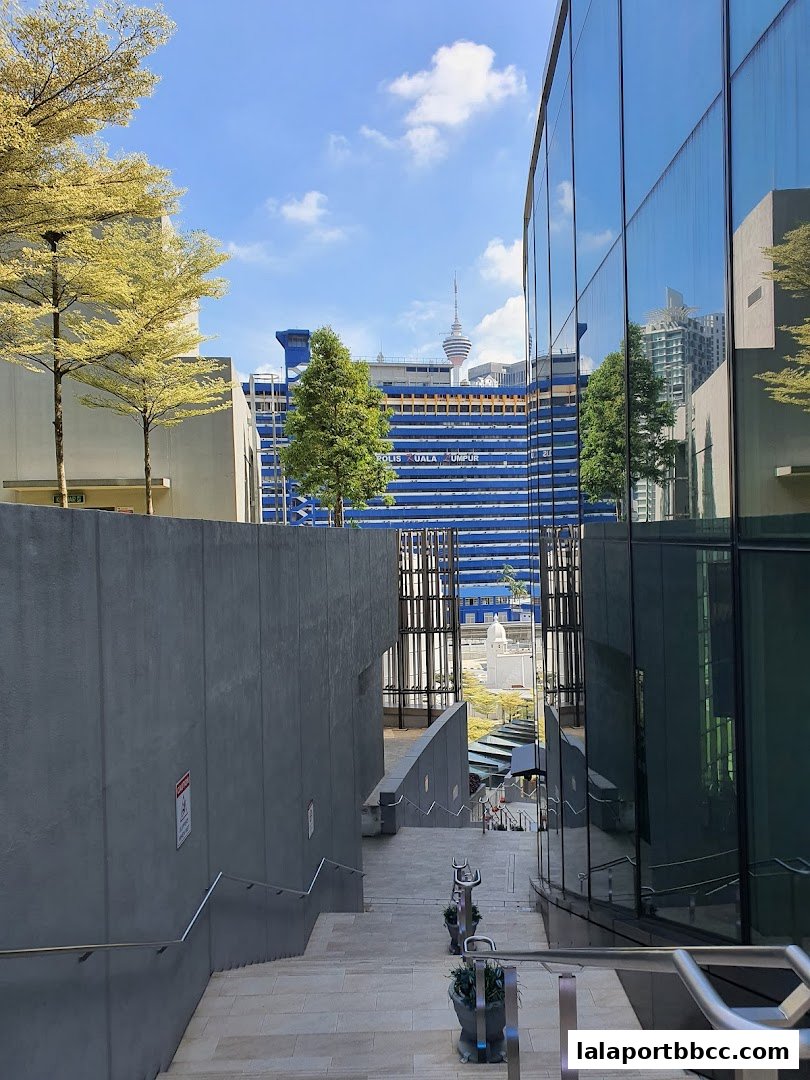 Outdoor stairs leading down with modern architecture and city skyline in the background.