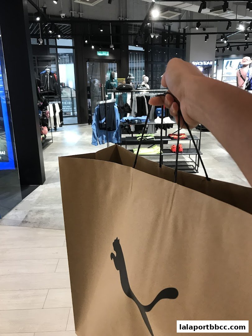A person holds a PUMA shopping bag inside a PUMA store, showcasing apparel.