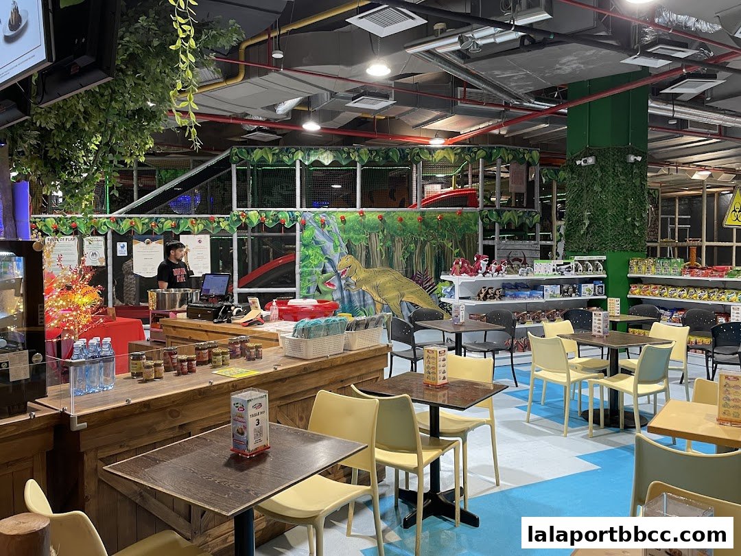 Interior of a dinosaur-themed indoor playground with seating areas and merchandise shelves.
