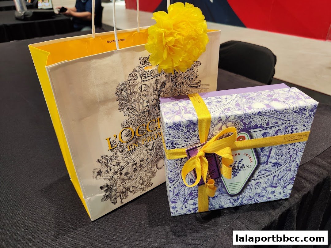 L'Occitane shopping bag and gift box with yellow ribbon and yellow pom-pom.