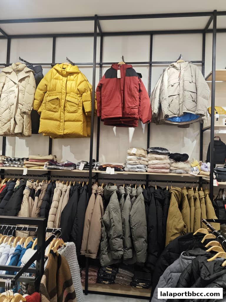 A retail shop displaying a variety of puffer jackets and other outerwear on racks and shelves.