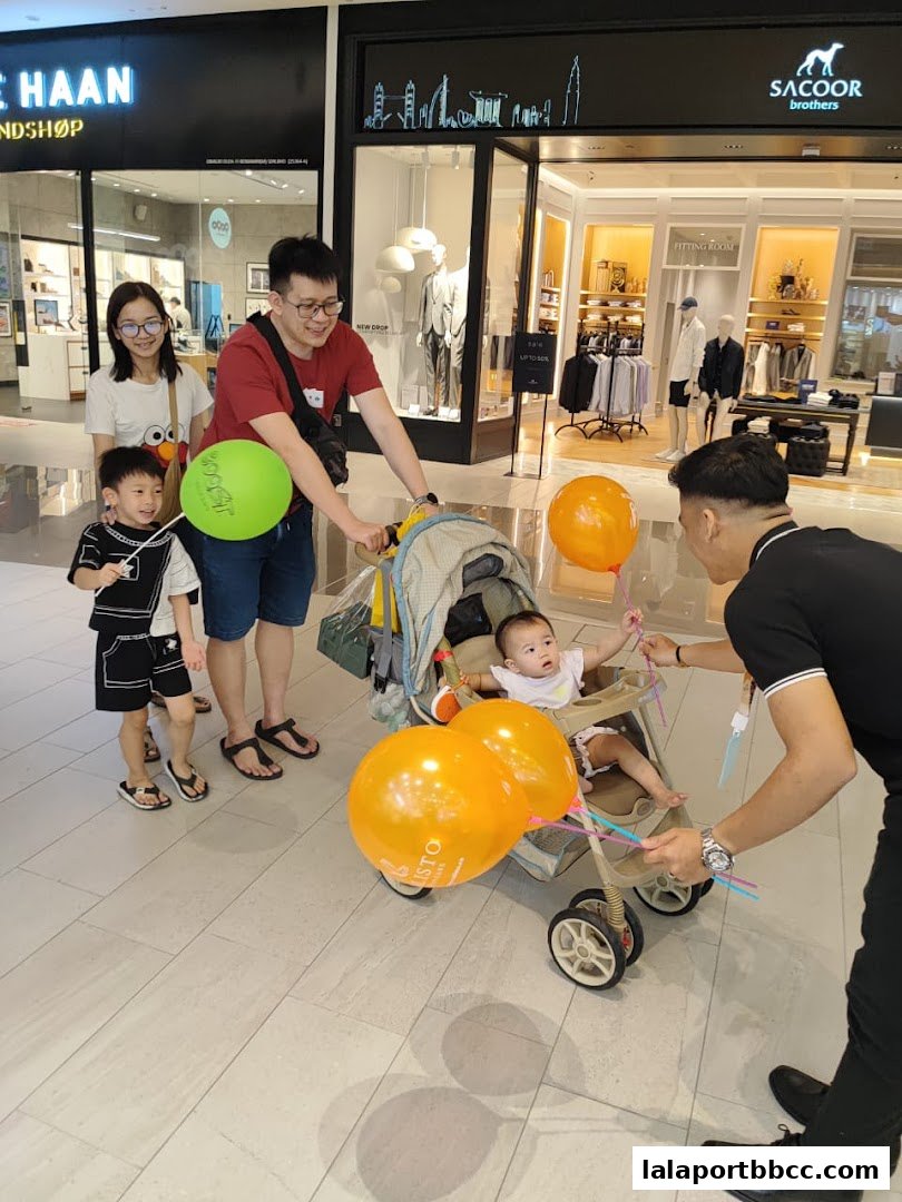 A family with balloons in front of shops at a mall.