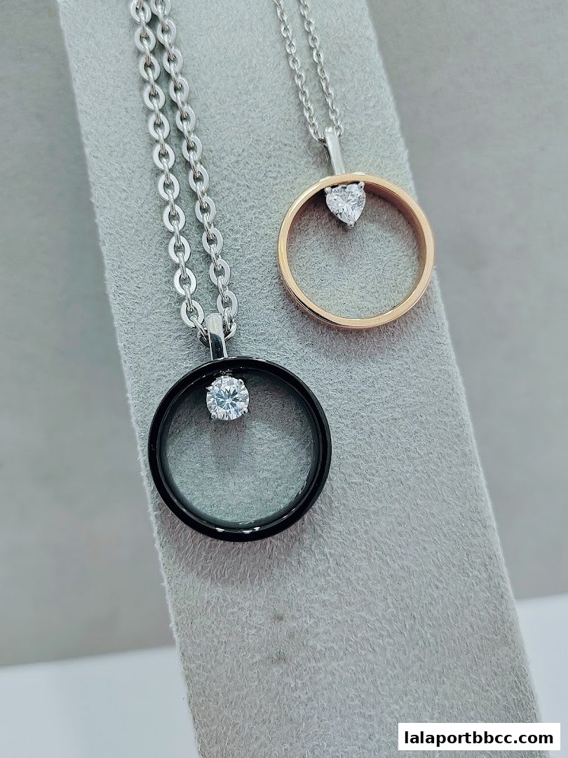 Two elegant necklaces with circular pendants and sparkling stones displayed on a grey surface.